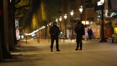 Två tungt utrustade poliser står på en ödslig gata i Paris, efter skottlossningen på Champs-Elysées.