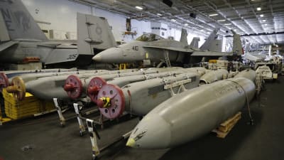 Två F/A-18C Hornet under däck på USS Carl Vinson, framför dem utrustning för elektronisk krigföring och extra bränsle
