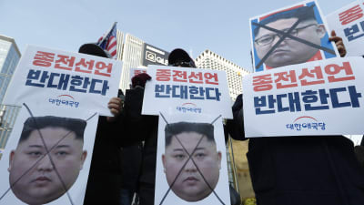 Demonstranter håller upp skyltar där Nordkoreas ledare Kim Jong-uns ansikte är utkryssat. 