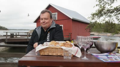 Tom Hildén sitter vid ett bord i stranden på Gullkrona, framför sig har han ett fat med örfilar