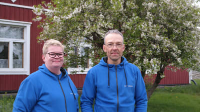 Värdparet i Gullkrona gästhamn står framför boningshuset och ett blommande träd