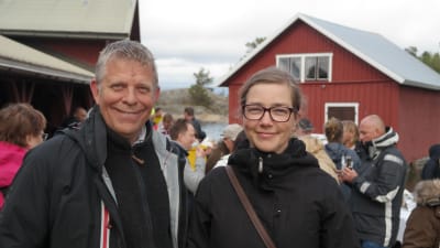 Alf och Joanna Norkko står på stranden på Gullkrona med folk i bakgrunden