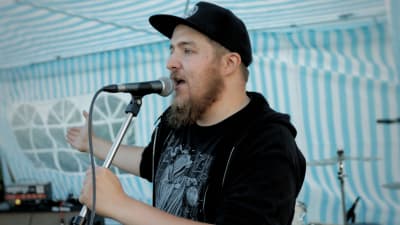 En man står och talar i en mikrofon.