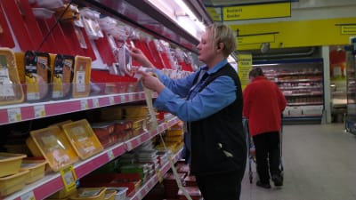 Monica Nurmi-Sinisalo limmar röda lappar på köttpaket i butiken