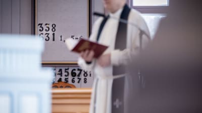 En präst håller i en psalmbok i kyrkan.