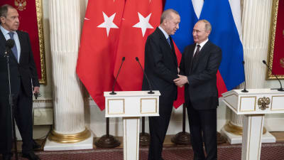 Venäjän ulkoministeri Sergei Lavrov katsoo kuvan oikealta reunalta kun Turkin presidentti Recep Tayyip Erdogan ja Venäjän presidentti Vladimir Putin kättelevät. Takana Turkin ja Venäjän liput. Edessä mikrofonit.