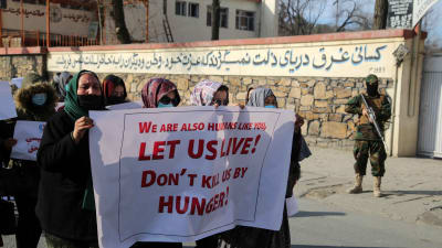 Kvinnor protesterar mot hungersnöden i Afghanistan. De bär ett plakat med texten "vi är också människor liksom ni. Svält inte ihjäl oss"