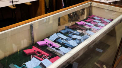 Flera färgglada handeldvapen i en vitrin.
