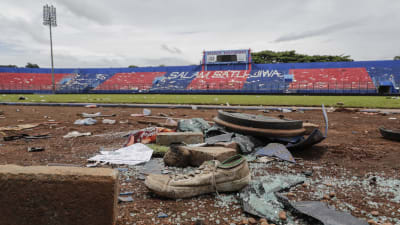 Skor, glassplitter och annat bråte på marken efter upplopp på fotbollsstadion i Indonesien.