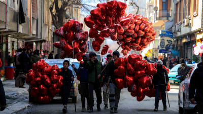En grupp unga män och pojkar med mängder av röda hjärtformade ballonger.