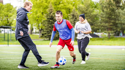 Nasrullah Akbari (i rött) och Nahwo Mahamud (i grått) spelar fotboll på evenemangsdagen inom ramen för projektet WELLcome - Wellbeing and integration through sports i Pansio i Åbo den 31.5.2022.