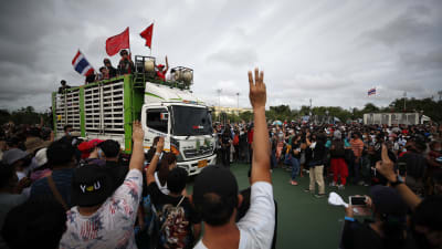 Personer står i folkmassa och håller upp händerna mot en lastbil med människor på flaket.