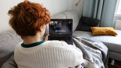 En person tittar på Netflix på soffan, via en bärbar dator.
