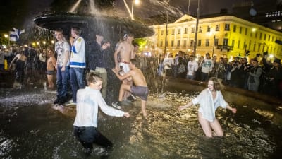 Flertal personer i våta kläder dansar i bassängen där Havis Amanda statyn står. 