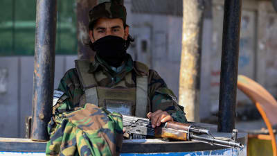 En talibansoldat med terrängdräkt och gevär.