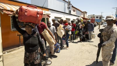 Haitiska medborgare bär sina tillhörigheter och är på väg att lämna landet.