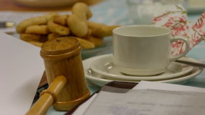 En kaffekopp och en ordförandeklubba på ett kaffebord.