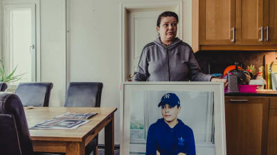 Carolina Sinisalo håller upp en stor tavla med sonen Robins foto.