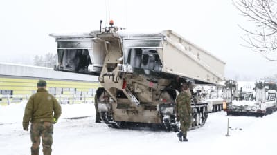 En pansarvagn transporterar en förflyttbar bro i ett snölandskap. På bilden syns också soldater.