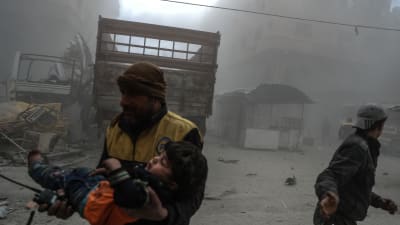 Biståndsarbetare hjälper ett skadat barn efter att Douma i östra Ghouta bombats.