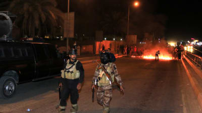Irakiska poliser framför en brinnande barrikad i Basra