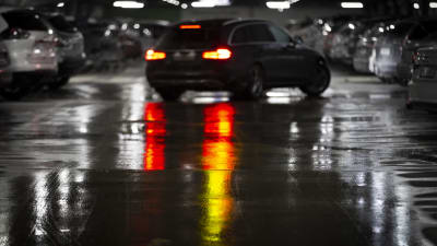 Bilar i ett mörkt och vått parkeringsgarage. 