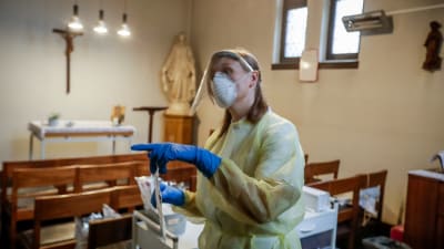 En sjukskötare i skyddsutrustning inne i kyrka