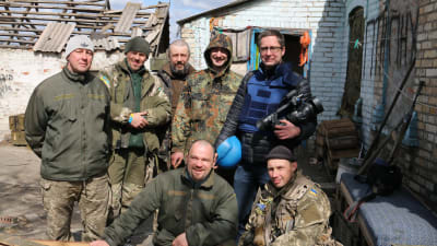 Antti Kuronen poserar med lokala män i kamouflagekläder i Ukraina med tv-kamera i handen.