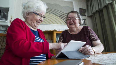 Kaksi mummoa käyttää tablettia kotona