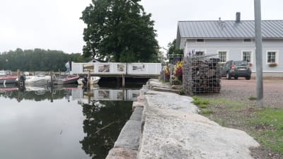 Bild av fiskhamnen i gamla stan i Ekenäs som visar hur nära vattenytan husen ligger. Till höger ett av husen vars gård ligger på en  brygga som går ut över vattnet. 