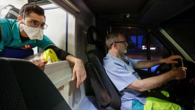 Två vårdare i en ambulans som kör genom ett nattligt Bryssel.