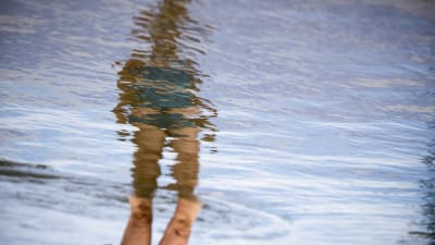 En kvinnas spegelbild syns i vågigt vatten