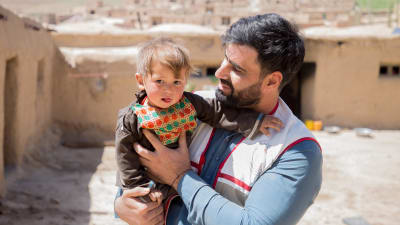 en afghansk pappa med ett barn i famnen