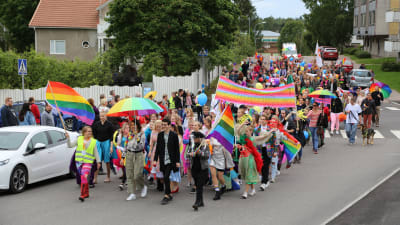 En färgglad prideparad med många människor går på en gata.