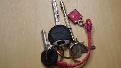 En nyckelknippa med en röd nyckelring som ligger på ett träfärgat bord. 