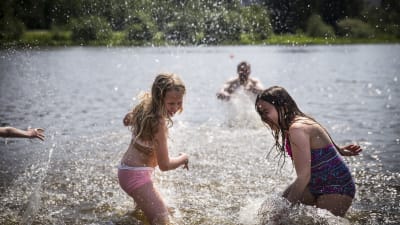Två barn i simkläder leker i en sjö