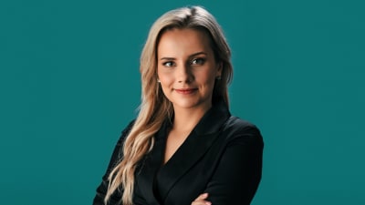 En kvinna med långt blont hår, iklädd en svart kostym.