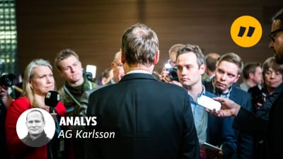 Juha Sipilä står med ryggen mot kameran, omringad av journalister.