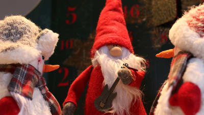 Julgubbe i from av docka med elbas och två snögubbar som tittar på