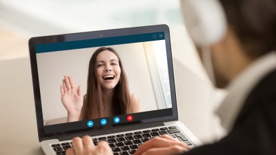 Leende flicka på dataskärm vinkar mot man som sitter vid datorn