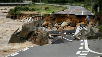 En man försöker korsa en kollapsad väg i Higashihiroshima i Japan.