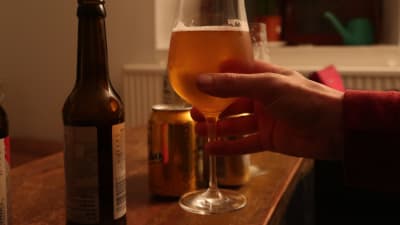 En hand lyfter ett vinglas med öl.