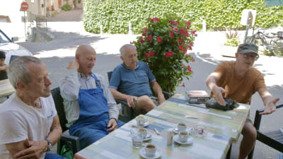 Fyra män sitter runt bord och diskuterar.