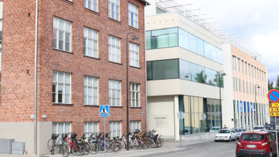 Äldre hus i tegel samt vitrappat nybygge i fyra våningar
