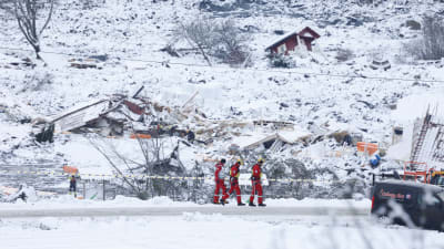 Räddningsarbetare går nära rasmassorna vid området där ett jordskred skedde 30.12.2020.