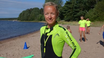 Charlotta Andström på en sandstrand med barn och ungdomar i bakgrunden.