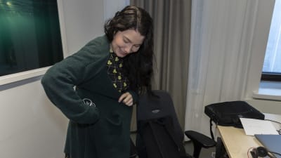 Ministeri Emma Kari laittaa taskuunsa kuulokejohtoa ja hymyilee.