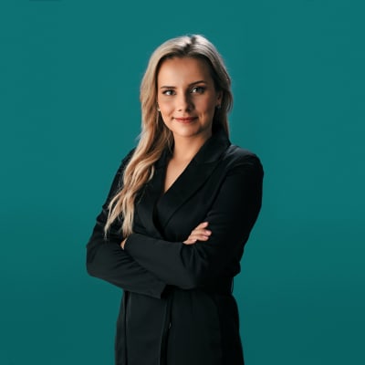 En kvinna med långt blont hår, iklädd en svart kostym.