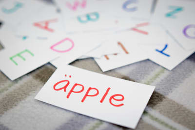 Kort med svenska ord, närmast kameran kort med ordet äpple.