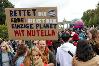 En klimatdemonstrant i Tyskland bär ett plakat med texten: "Rädda världen, det är den enda planeten med Nutella"